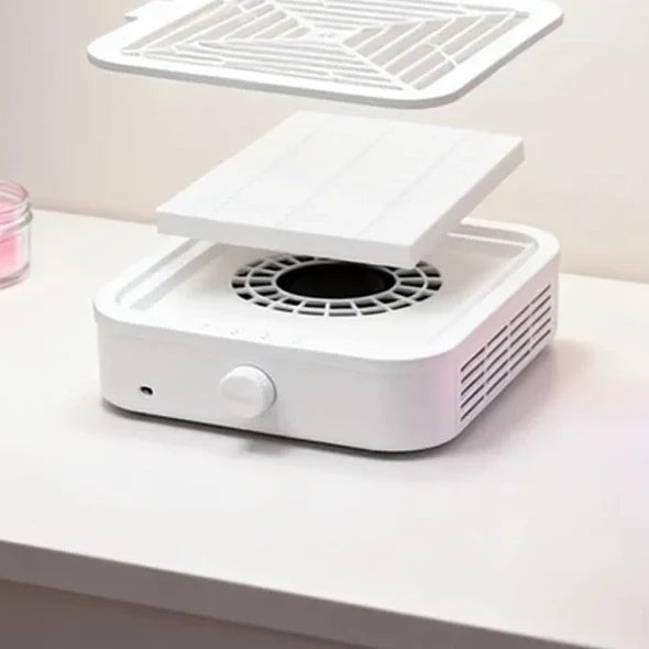 Vue éclatée de l'aspirateur : grille amovible, filtre et turbine, sur une table de manucure